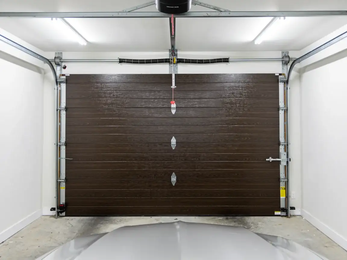 A closed brown garage door with a torsion spring and opener.